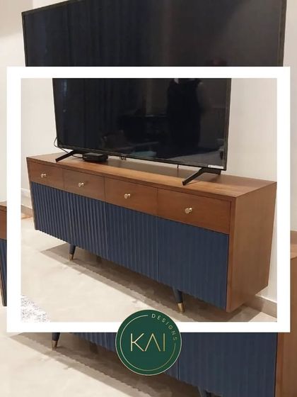 This TV unit combines a rich wood grain with a deep blue fluted finish on the cabinet doors. The tapered legs with brass tips add a mid-century modern touch, creating a piece that is both stylish and highly functional.