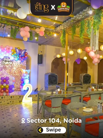 A wide shot of the dining area decorated for a butterfly-themed 2nd birthday, with a pink and purple balloon arch and a sequin backdrop.