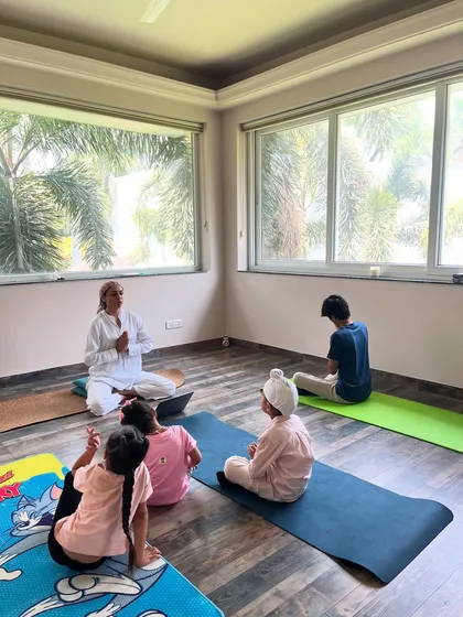 This is what my kids' yoga sessions are all about: playful movement and happy smiles. I guide a small group of children, including one in a fun scorpion-like pose, creating a warm and interactive space for mindful movement for kids.