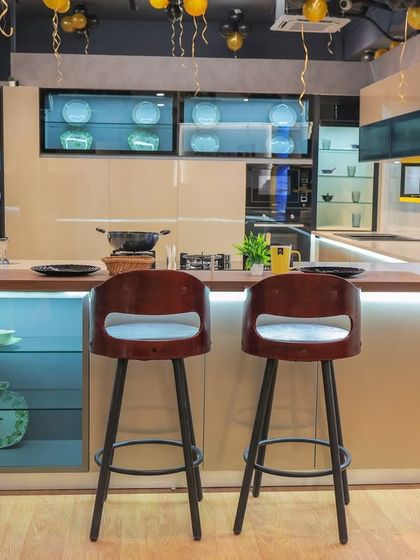 A wide shot of our Rohtak showroom, decorated for its grand opening. This kitchen display features a modern island with a breakfast bar, glass-fronted upper cabinets, and integrated lighting, showcasing a perfect space for cooking and socializing.