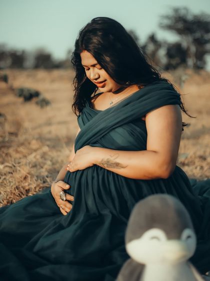 A quiet moment of reflection for this mom-to-be. The deep teal gown drapes beautifully in this seated outdoor pose, creating a serene and artistic portrait.