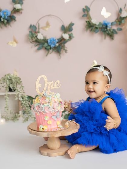 A gentle touch and a sweet smile before the smashing begins. These are the quiet, anticipatory moments of a first birthday shoot.