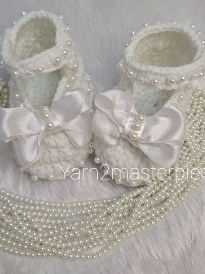 These white booties feature a large satin bow and are detailed with pearls along the strap and bow center, creating a very formal and elegant look.
