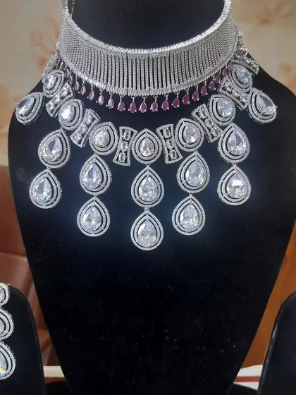 A glamorous American Diamond necklace set with large teardrop stones and a ruby-accented choker.