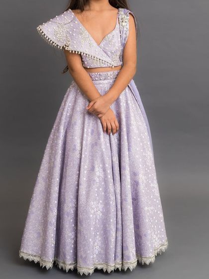 A bestseller, this lilac brocade lehenga features a one shoulder blouse with pearl detailing and a classic, elegant skirt.