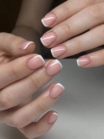 A perfectly executed classic French manicure on short, square nails. The clean lines and natural-looking base are the hallmarks of this timeless style.