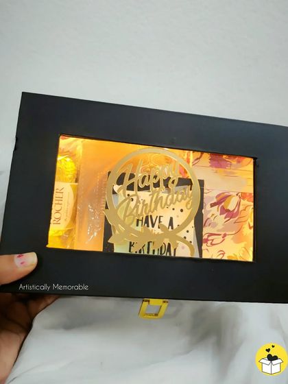 A birthday hamper with a window to peek inside. The warm light from within hints at the goodies waiting to be discovered.