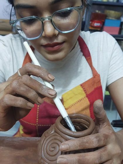 A close-up of a student focused on her work, using a tool to perfect the details on her coiled pot. The studio is a place for learning new skills, and I love sharing the techniques of hand-built pottery with everyone who walks through my door.