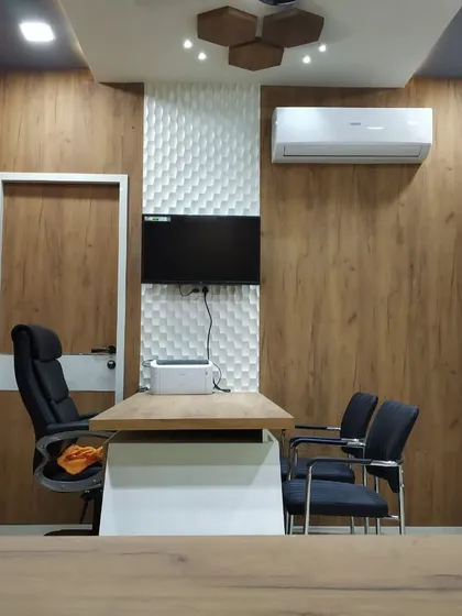 The doctor's consultation room in the clinic continues the design theme with wood-paneled walls and a textured white accent panel. The space is designed to be professional, clean, and comfortable for patients.