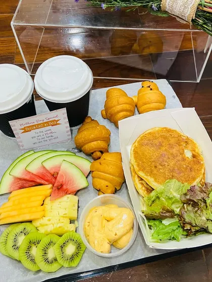 A close-up of the delicious breakfast platter for Mother's Day, including pancakes, croissants, fresh fruit, and coffee.