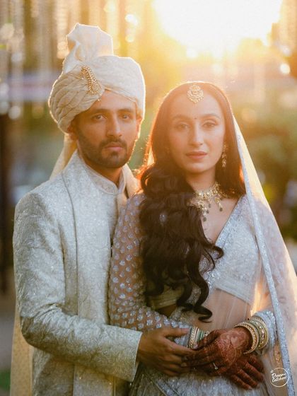 A powerful portrait of a couple bathed in the golden light of sunset on their wedding day. Their direct gaze and classic pose create a feeling of strength, soulfulness, and deep connection.