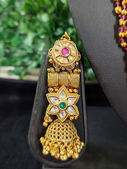 A close-up of an earring from the for-sale set with a floral choker. The design features intricate metalwork and a classic jhumka style.