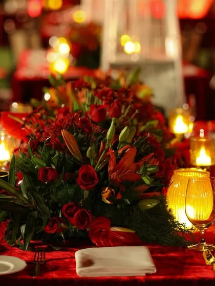 The dining tables were dressed in rich red velvet, with a long runner of red roses and lilies, surrounded by the warm glow of candles for an intimate yet grand dinner.