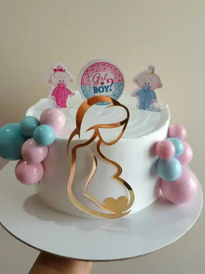 A sweet gender reveal cake with a "Girl or Boy?" topper and an acrylic silhouette of an expecting mother.