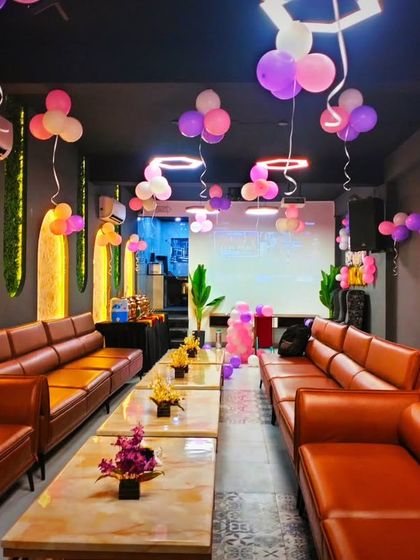 Another angle of the party for Amyra, showing the long seating arrangement and the festive balloons hanging from the ceiling.