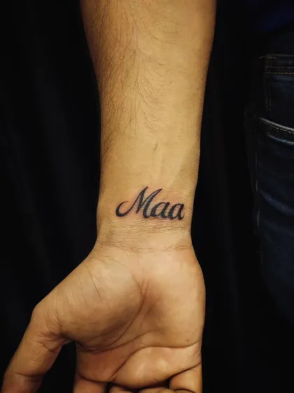 A classic 'Maa' (Mother) tattoo on the wrist. We use clean, elegant script to create a timeless tribute to a mother's love.