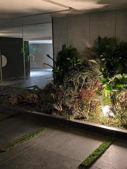 A final look at the completed project at night. The strategic lighting creates a warm glow, highlighting the different plant textures and making the space feel welcoming and alive.