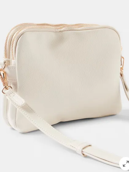A side view of the off-white Australia Crossbody, showing its slim profile and dual-zip compartments that help keep you organized.
