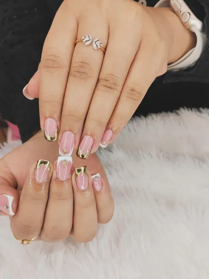 A modern and chic French manicure with gold accents. This design features a squared-off tip in white and pink, with delicate gold lines and studs for a touch of glamour.