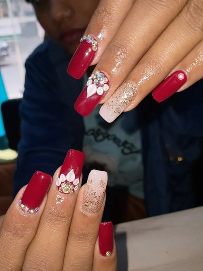 A bold and beautiful bridal design. This set features long, square-shaped nails in a vibrant red, with accent nails in a soft nude glitter and decorated with intricate 3D white flowers and stones.