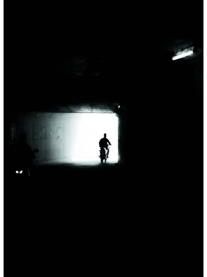 a silhouette of a biker at the end of a dark tunnel. i love playing with light and shadow, a technique that is central to creating effective dark mode interfaces.