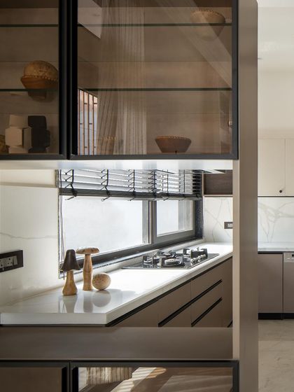 A detail of the open kitchen and dining area, showing how custom cabinetry with glass doors provides a view into the kitchen, connecting the two spaces.