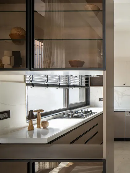 A detail of the open kitchen and dining area, showing how custom cabinetry with glass doors provides a view into the kitchen, connecting the two spaces.