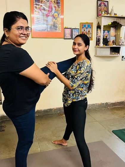 Here I am assisting a younger student with a standing balance pose. My classes are for all ages, and I provide individual attention to help everyone grow in their practice.