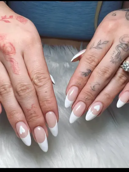 A soft and pretty take on the French manicure, these long almond nails feature a classic white tip with a small heart detail on the accent nail.