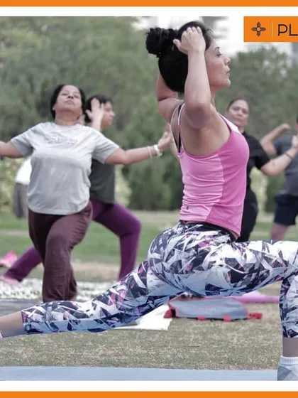 It's not all high-intensity. We also take time for recovery and flexibility with outdoor yoga and stretching sessions. Here, a member holds a lunge pose, focusing on form and breathing in a calm park setting.