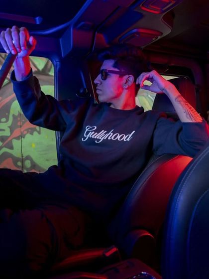 This image uses the interior of a vehicle and dramatic red and blue lighting to create a moody, cinematic feel. It's a creative approach to a streetwear lookbook that captures a specific nighttime vibe.