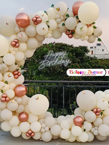 Our decorations are perfect for any location, including this beautiful outdoor terrace setup in Bangalore. This features an elegant circular frame adorned with a dense arch of pastel and rose gold chrome balloons, butterfly accents, and a central 'Happy Birthday' neon sign, creating a perfect photo opportunity.