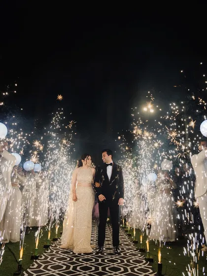 A spectacular sangeet night entrance. The couple walks down an aisle flanked by friends and dazzling cold-pyro sparklers, capturing the high energy and magical atmosphere of the celebration.