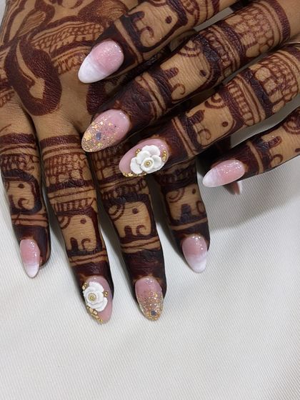 A close-up view of the detailed 3D flower and gold glitter accent nail from this popular bridal design.