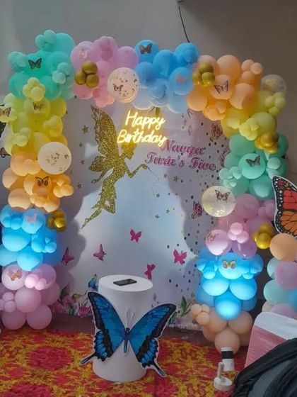 An enchanting fairy and butterfly theme. This setup uses a custom backdrop with a fairy silhouette, a pastel balloon arch, and butterfly cutouts, with internal lighting to make the balloons glow.