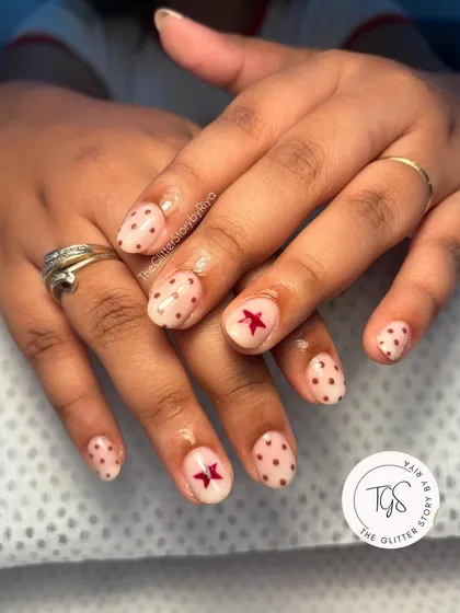 A cute and simple design with a sheer nude base, brown polka dots, and a single red star accent on each hand.