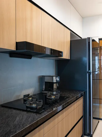 This shot shows the full length of the parallel kitchen, with the refrigerator neatly integrated at the end. The consistent use of materials creates a cohesive and elongated feel.
