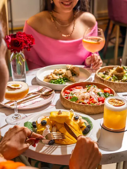 A vibrant lifestyle shoot for Blah Bombay, capturing the energy of a weekend brunch. This image focuses on the social experience of dining, showing colorful dishes and cocktails shared between friends, a style that helps customers envision themselves in the space.