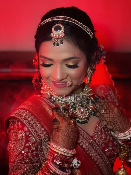 A close-up of the bride's radiant smile and glowing skin under the warm red lighting of the venue.