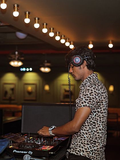 A side profile of me at the decks, with the warm club lighting in the background.
