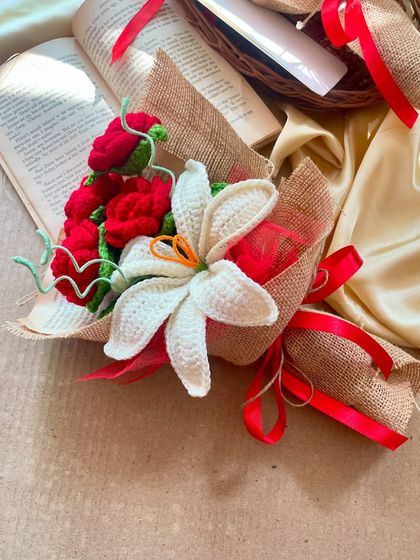 A romantic arrangement of red roses and a white lily, styled with an open book to evoke a classic love story. These forever flowers are perfect for an anniversary or a special declaration of love.