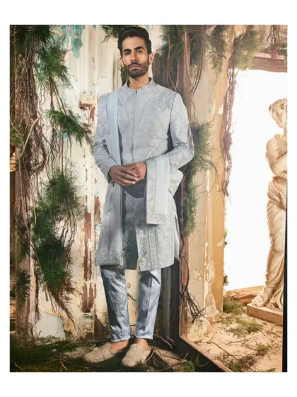 A full view of the textured blue sherwani set. Paired with tailored trousers and elegant footwear, it presents a complete, polished look for any wedding celebration.