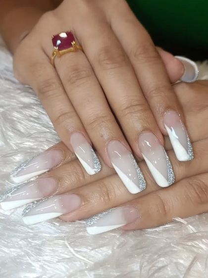 A glamorous and modern French design. This set features a diagonal white tip with a border of fine silver glitter on long, coffin-shaped nails for a chic and eye-catching look.