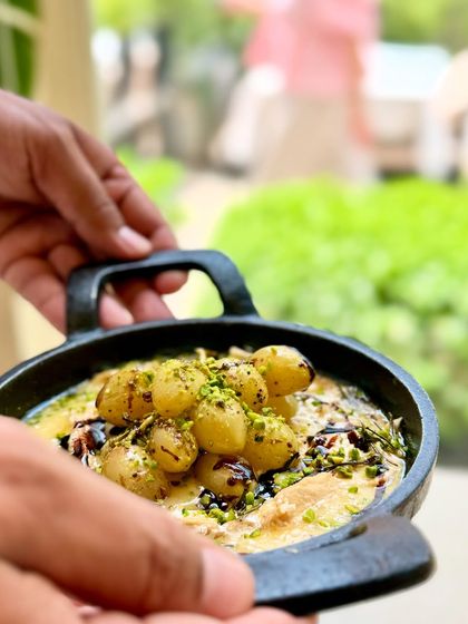 We sourced the finest Kumaoni grapes for this unique dish. Here, our chef holds a skillet of oven-roasted grapes on melted hot brie, a perfect pairing of sweet and savory.