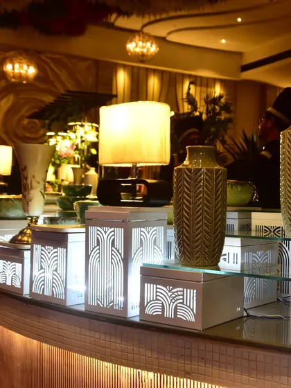 An elegant buffet station with illuminated art-deco style risers and decorative vases. We meticulously craft every detail to ensure our food stations enhance the overall aesthetic of your event.