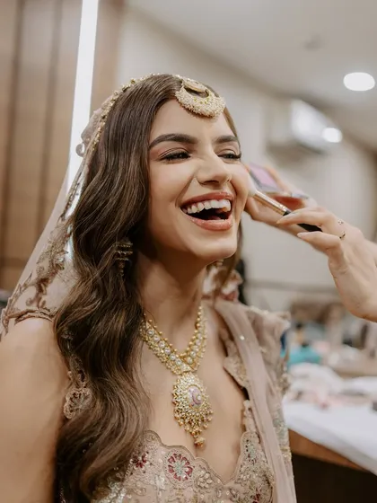 A candid moment of laughter during the getting-ready process. This bride shines in her pastel lehenga with a soft makeup look that feels like her true self.