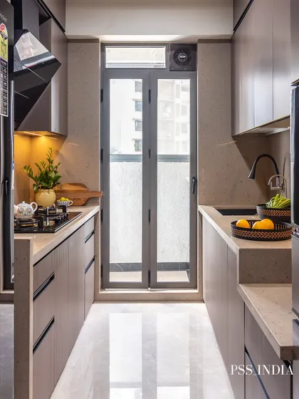 A perfect example of a modern galley kitchen. The neutral, flat-panel cabinets create a sense of spaciousness, while the glass door at the end floods the area with light. Simple styling with fruit and plants adds a touch of life.