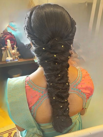 A voluminous fishtail braid with small pearl-like accessories. This is a great option for an evening event, adding a touch of sparkle to the hair.
