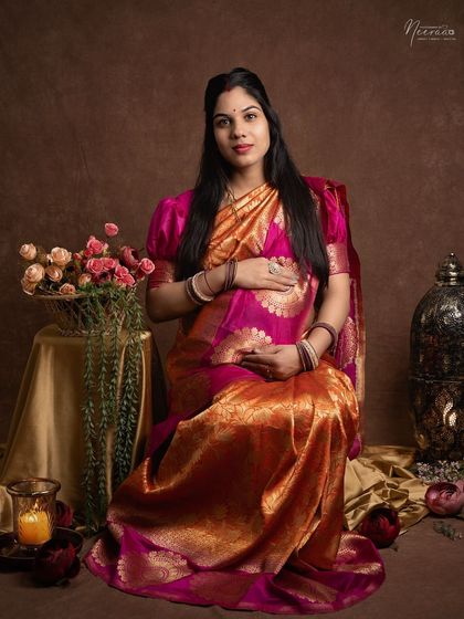 Looking directly at the camera, this mom-to-be radiates confidence and grace. The traditional saree and props add a layer of cultural richness to her maternity portrait.