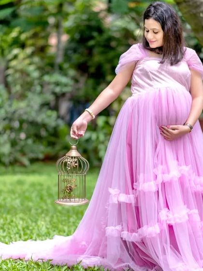 The client looks lovely holding a birdcage prop, adding a whimsical touch to her maternity shoot in my light purple ruffled gown.